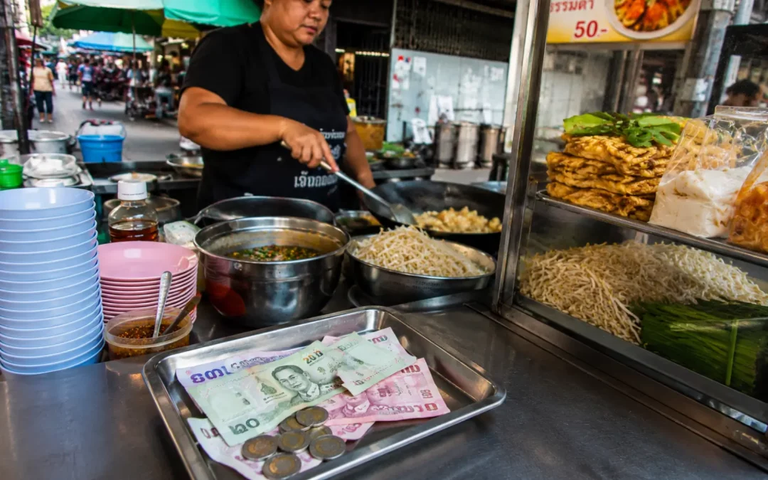Étal de street food à Bangkok avec bahts thaïlandais pour illustrer le budget repas