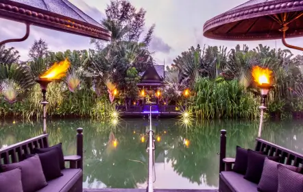 Restaurant Black Ginger à Phuket, au milieu d’un jardin tropical et d’un plan d’eau, éclairé par des torches à la tombée de la nuit
